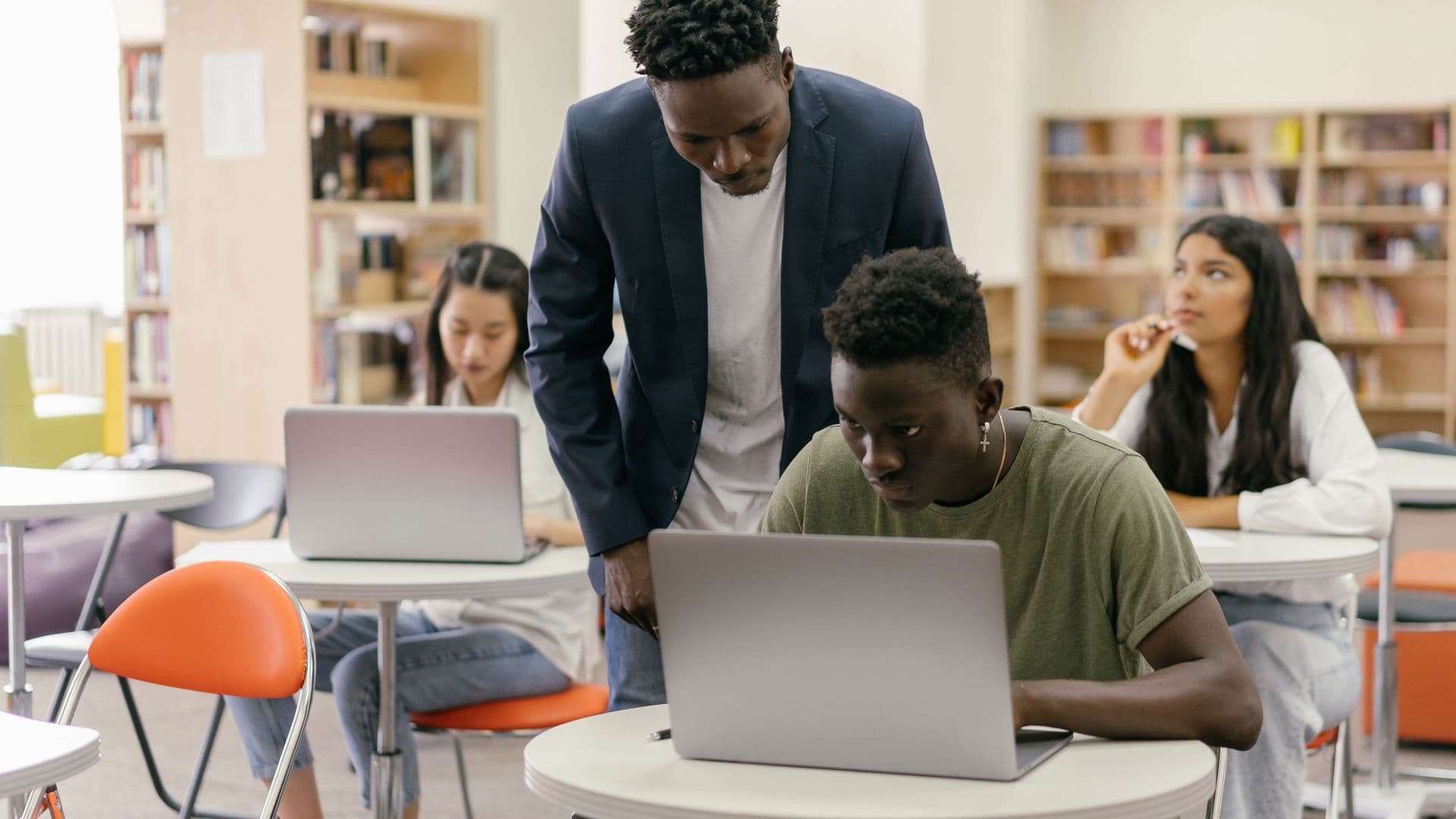 A teacher helping a student on a laptop in the classroom
